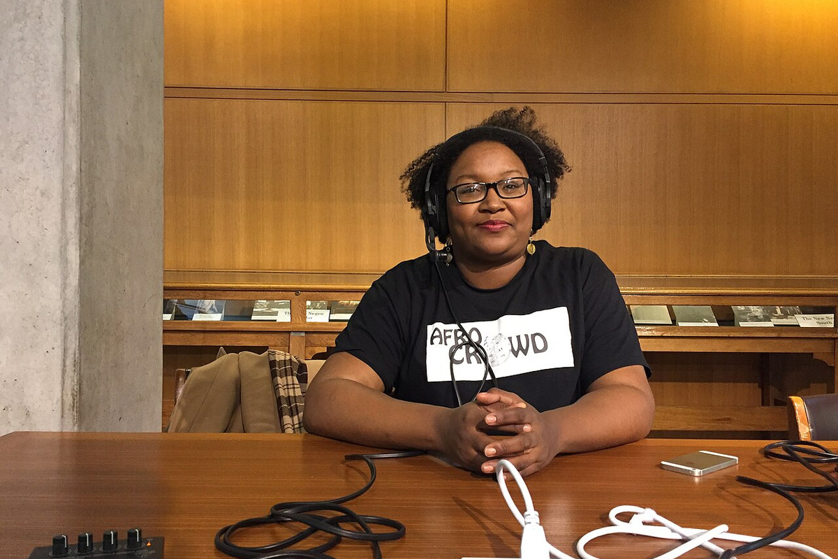 A podcast host recording with closed-back headphones and a microphone